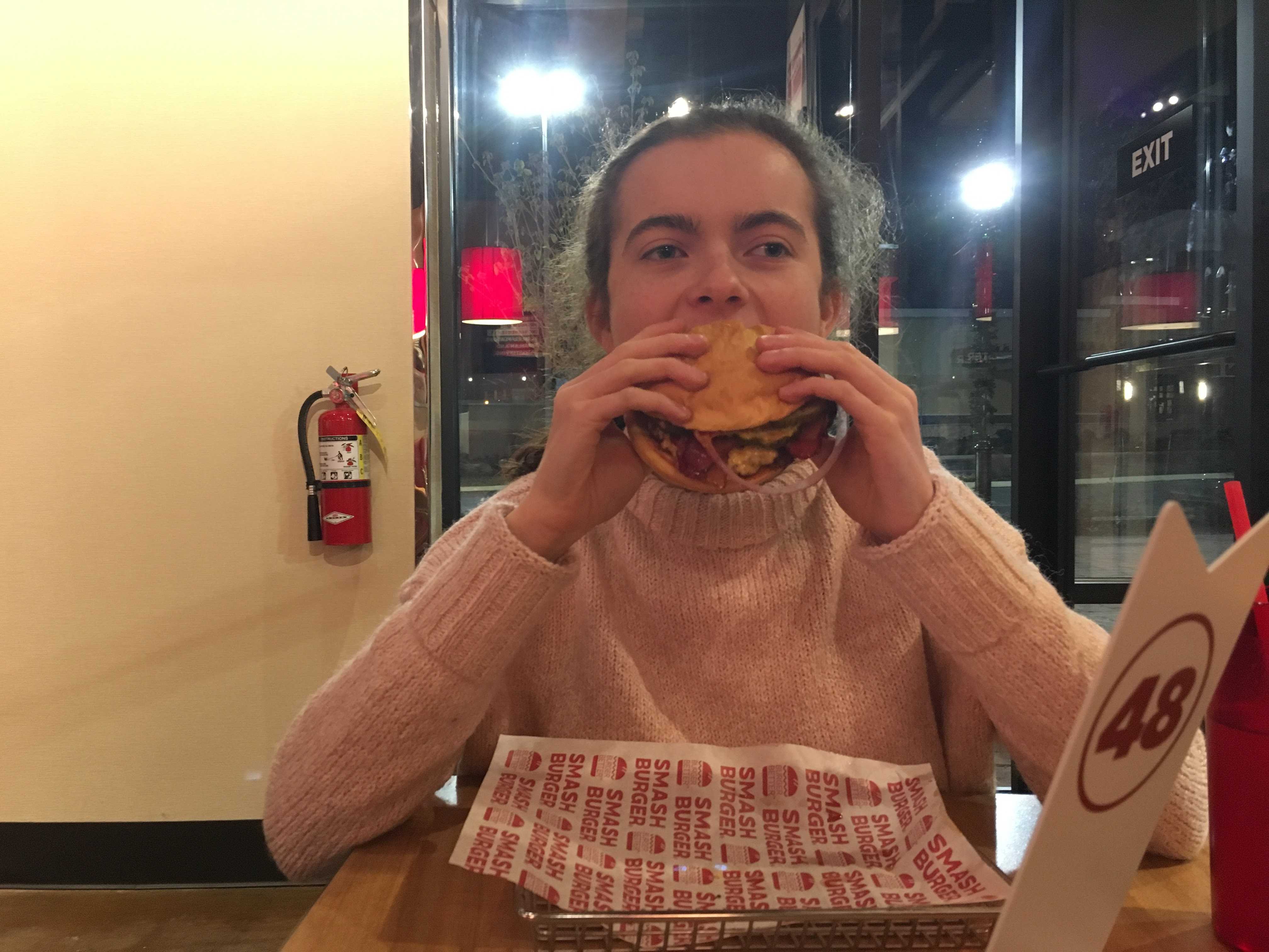 Andrea takes her first bite of her burger.