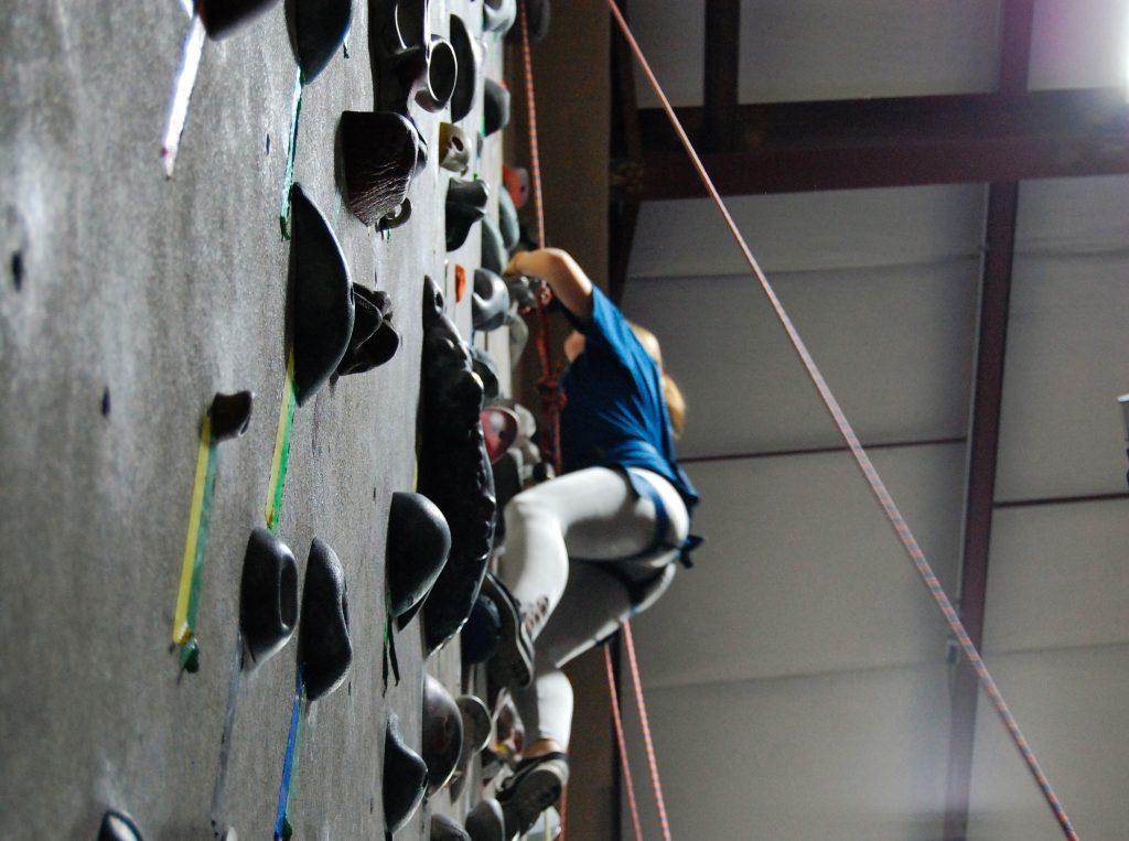 Freshman Maryn Schellenberg, new to rock climbing, climbs on a set of rocks for beginners. Photo by Meliha Anthony.