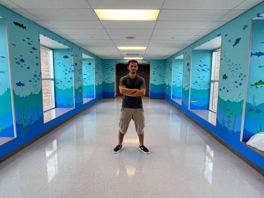 Ryan stands in the mural hallway. Photo courtesy of Ryan.
