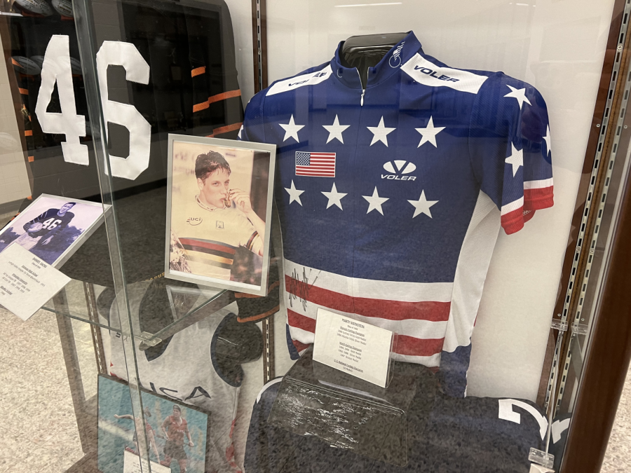 A photo of former cyclist Marty Nothstein sits in front of a signed jersey in a display case in the Emmaus High School athletic lobby. In Dec. 2021, Nothstein, a 1989 graduate of EHS, was arrested and charged with multiple offenses. Photo by Thomas Hartill.