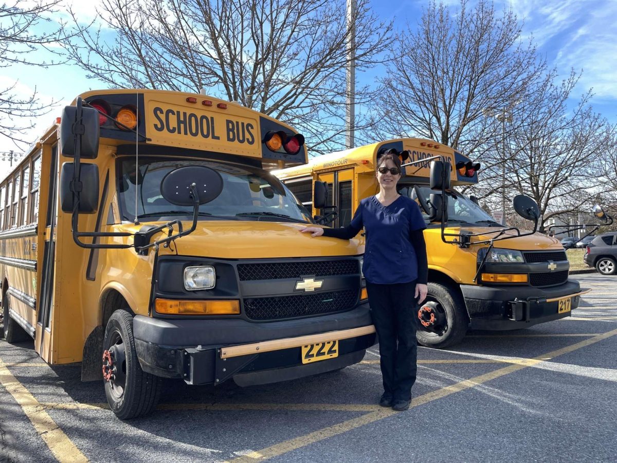 Bus driver and cafeteria worker Lisa Stenroos stands proudly beside her bus outside the EHS loading dock on Feb. 7, 2024. Photo by Katerina Starry.