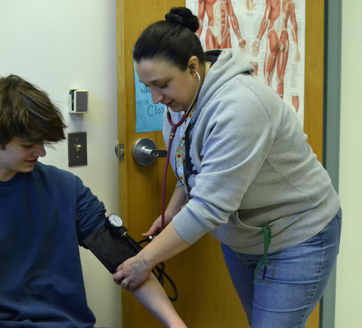 Valerio treats EHS student in nurse’s office by taking blood pressure. Photo by Thiffany Reimao.