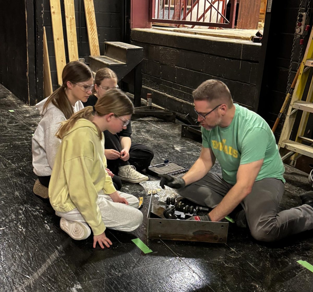 Kollar assists freshman Kayla Ofner, junior Bree Schoonover, and freshman Anna Williams on making sets for “Mama Mia!” backstage. Photo by Zoe Hulings.